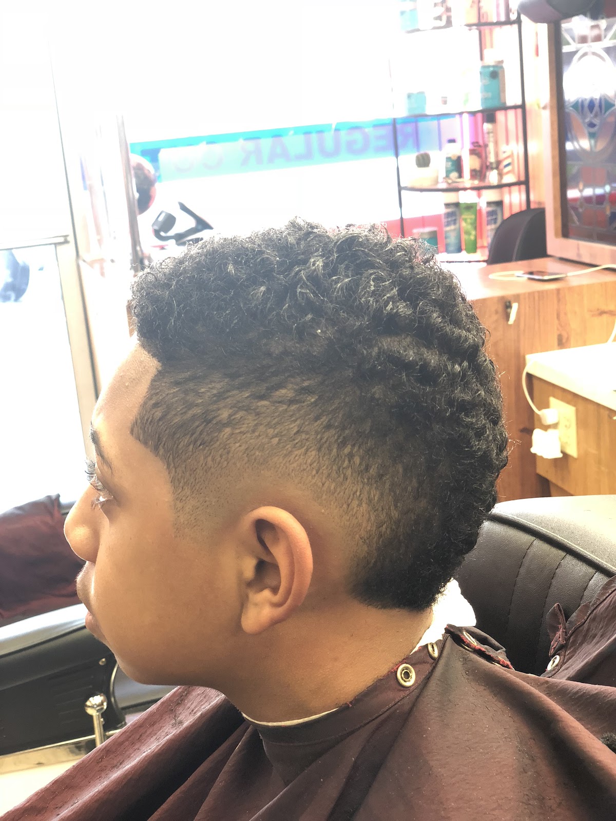 Side view of a finished cut: curls on top faded down to the skin